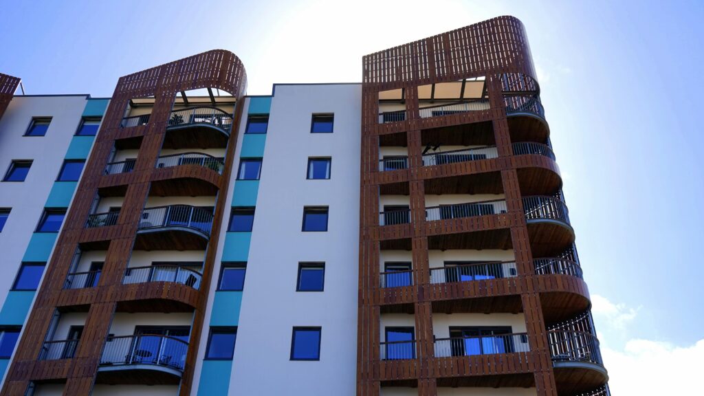 Explore the contemporary design and architecture of urban apartments with wooden accents and blue sky backdrop.