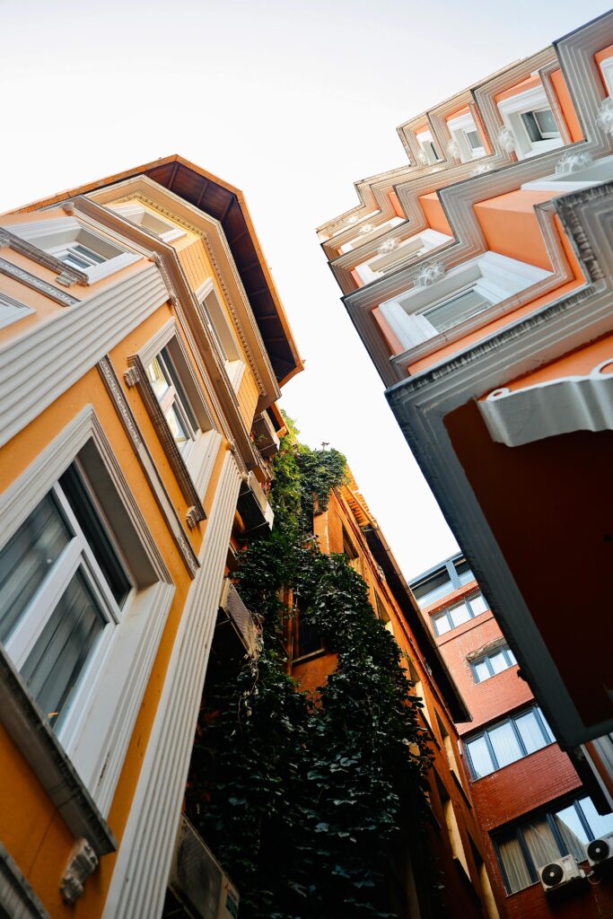 Captivating upward view of vibrant orange buildings with ivy, capturing urban charm.